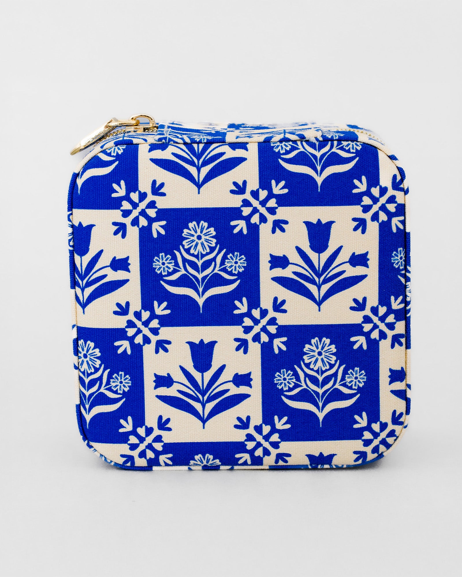 A square zippered pouch featuring a classic blue and cream floral block print pattern, with a gold zipper pull, shown against a plain light gray background.