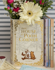 Decorative book titled 'The House at Pooh Corner' with flowers on a striped background