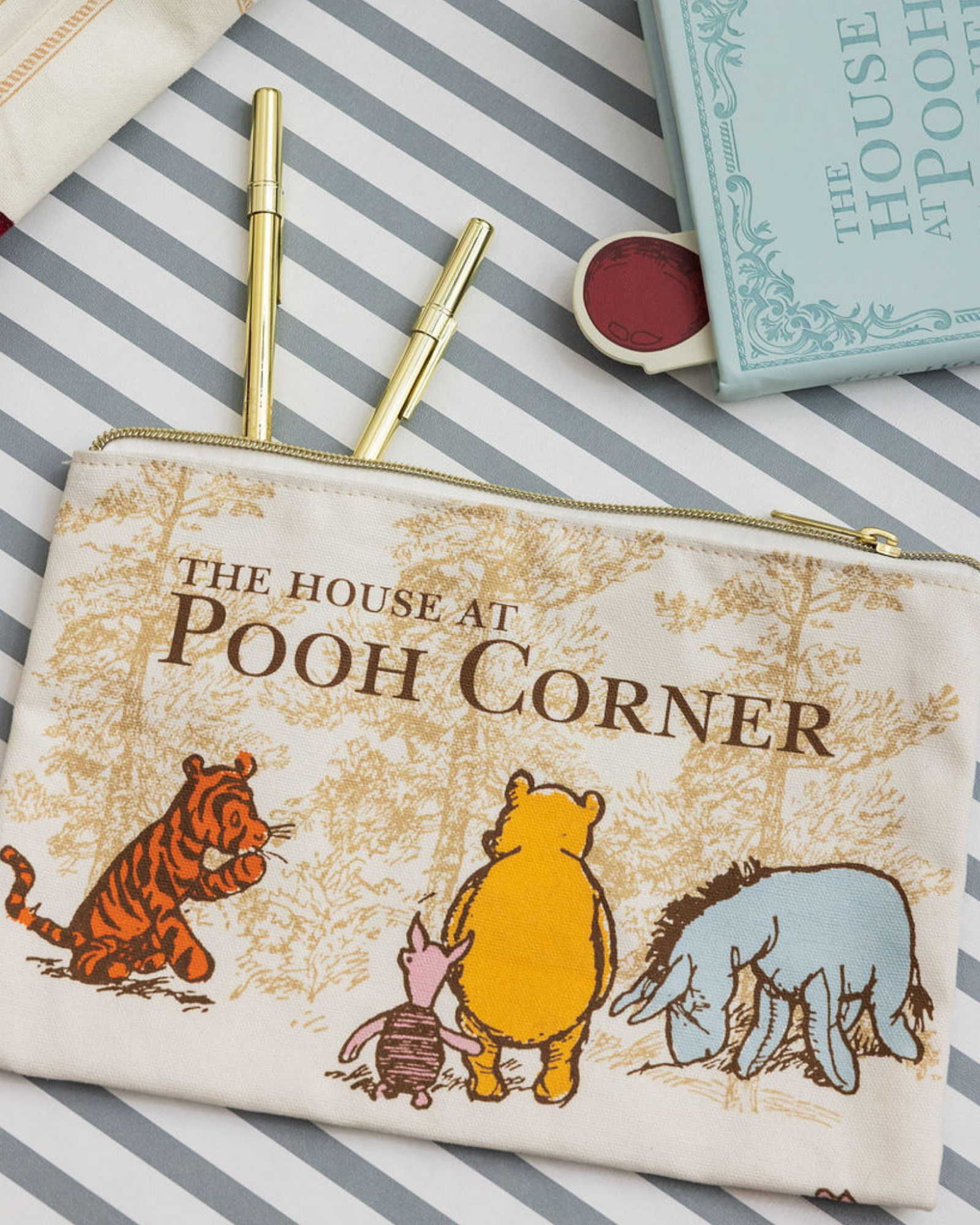 Pouch with 'The House at Pooh Corner' design featuring Pooh and friends on a striped background.