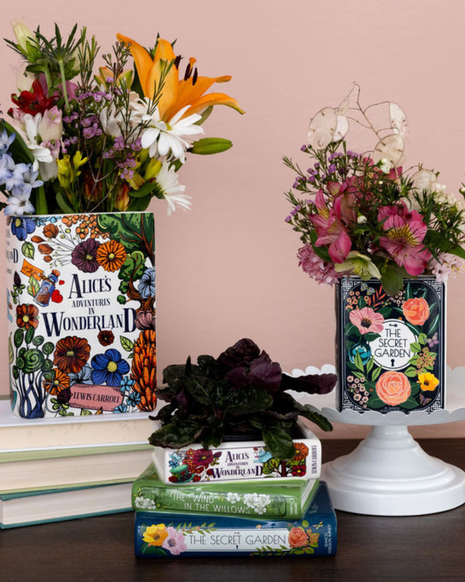 Floral arrangements in books with 'Alice's Adventures in Wonderland' and 'The Secret Garden' covers on a wooden surface.