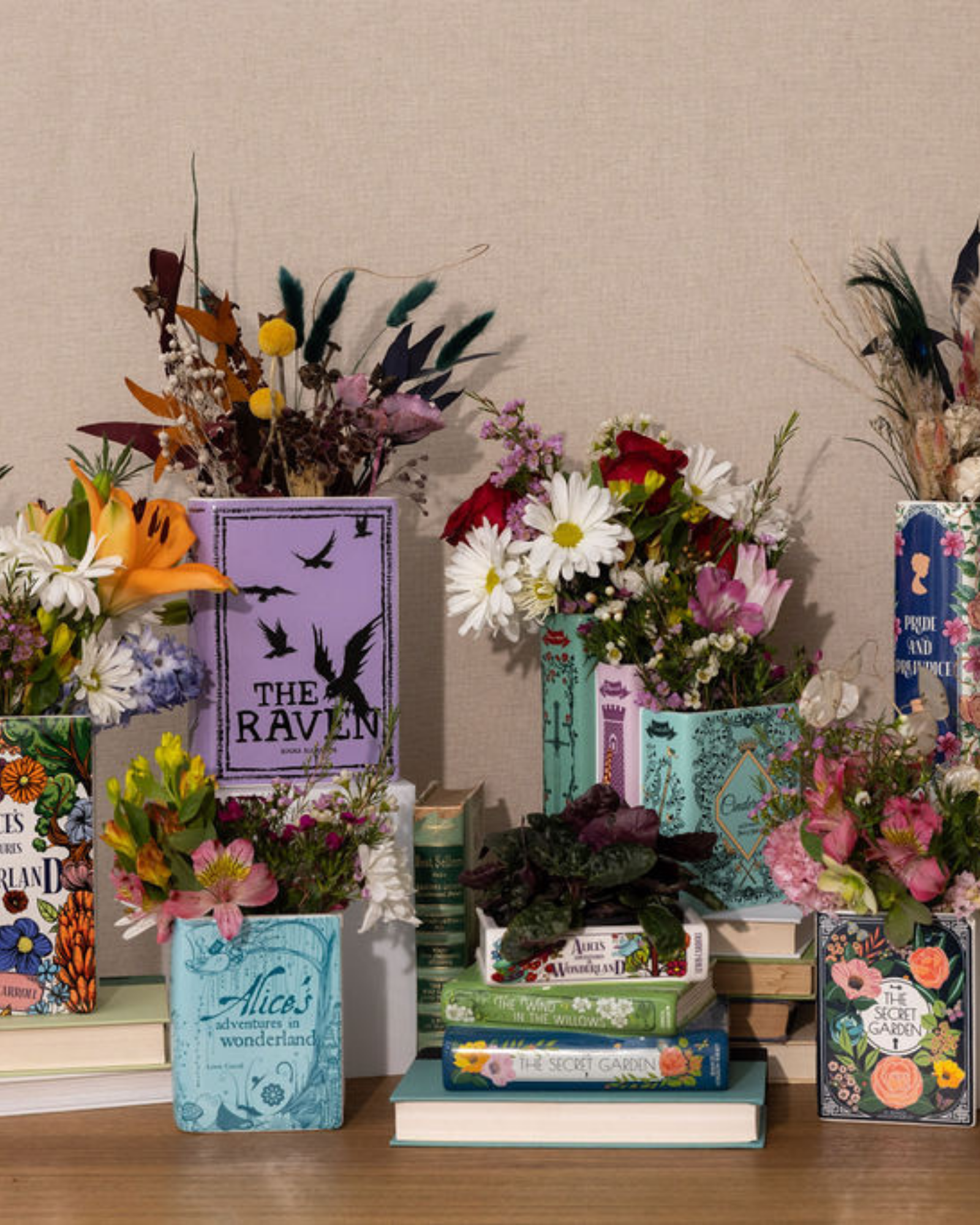Decorative display of books and flowers on a wooden surface with a neutral background