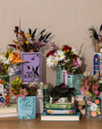 Decorative display of books and flowers on a wooden surface with a neutral background