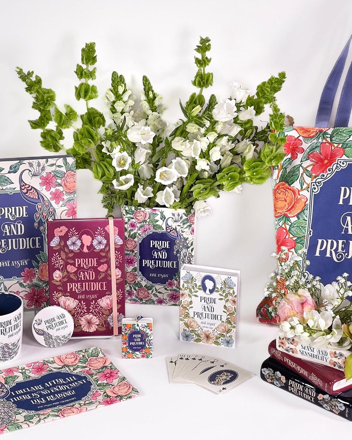Collection of 'Pride and Prejudice' themed books, mugs, and decor items on a white background with flowers.