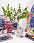 Collection of 'Pride and Prejudice' themed books, mugs, and decor items on a white background with flowers.