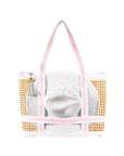 Raffia beach bag with gold accents and a white hat inside on a white background