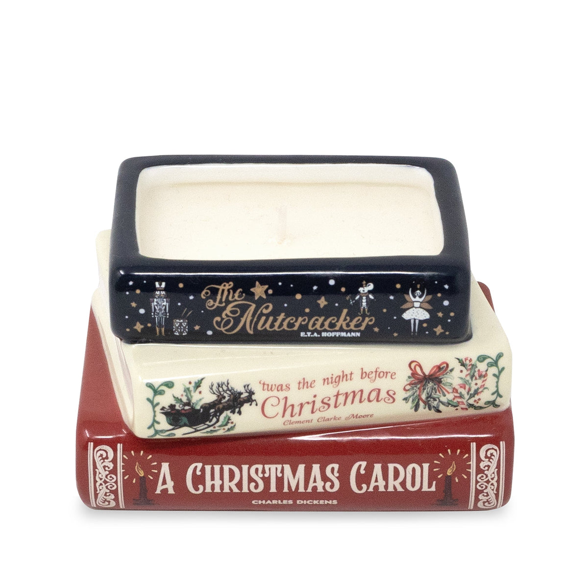 A ceramic Christmas-themed book stack candle holder featuring 'A Christmas Carol' in red, a cream 'Christmas' book, and a navy 'The Nutcracker' book with gold lettering and illustrations, set against a plain white background.