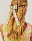 Woman with long blonde hair wearing a floral headband against a light background