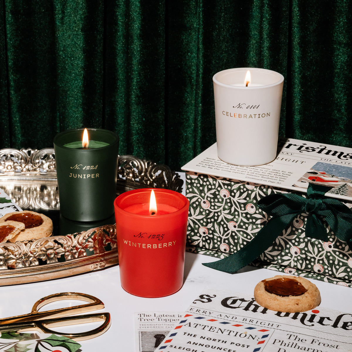 Three lit scented candles from Amelin Archive in juniper, celebration, and winterberry