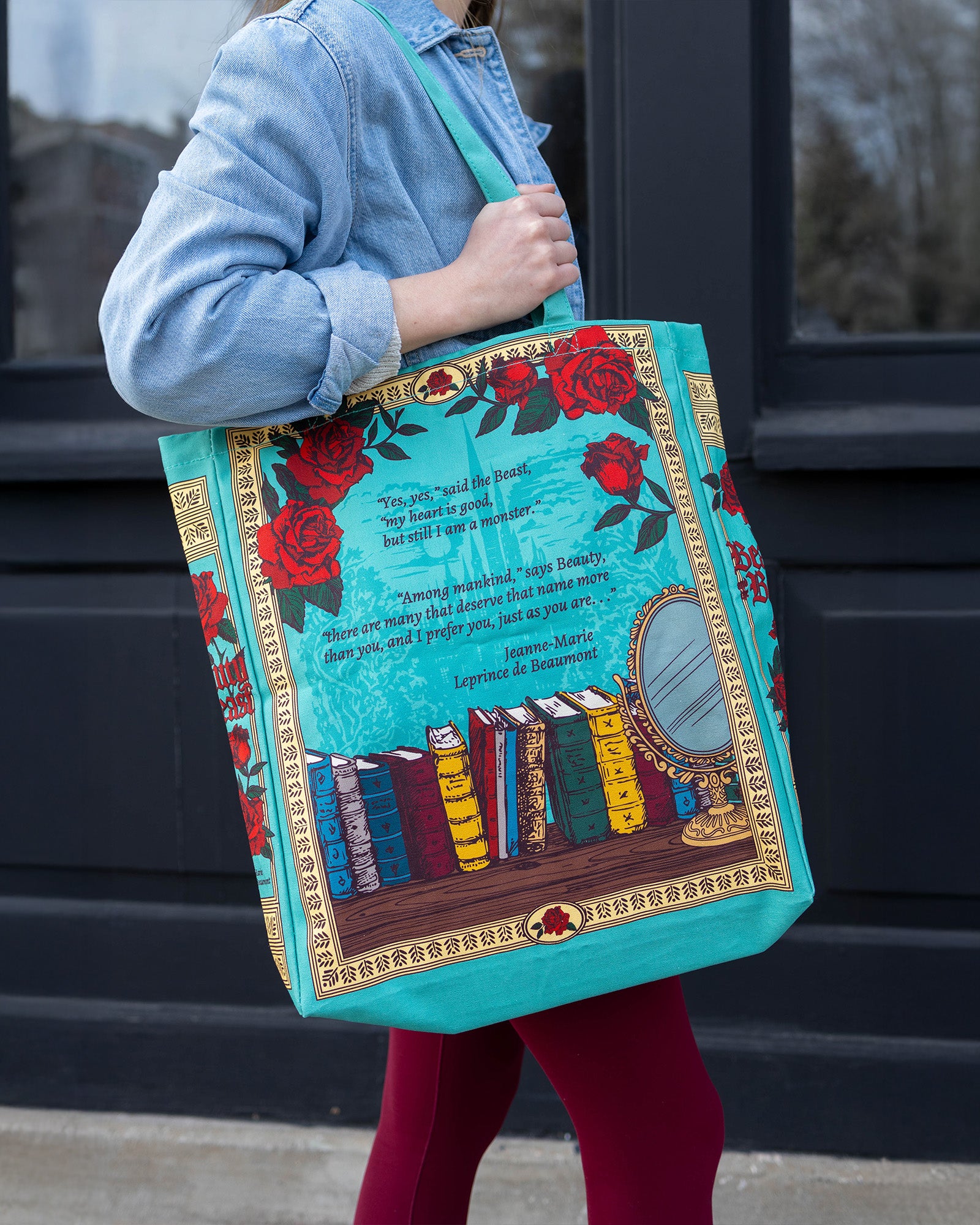 Person holding a colorful tote bag with book design and floral elements.