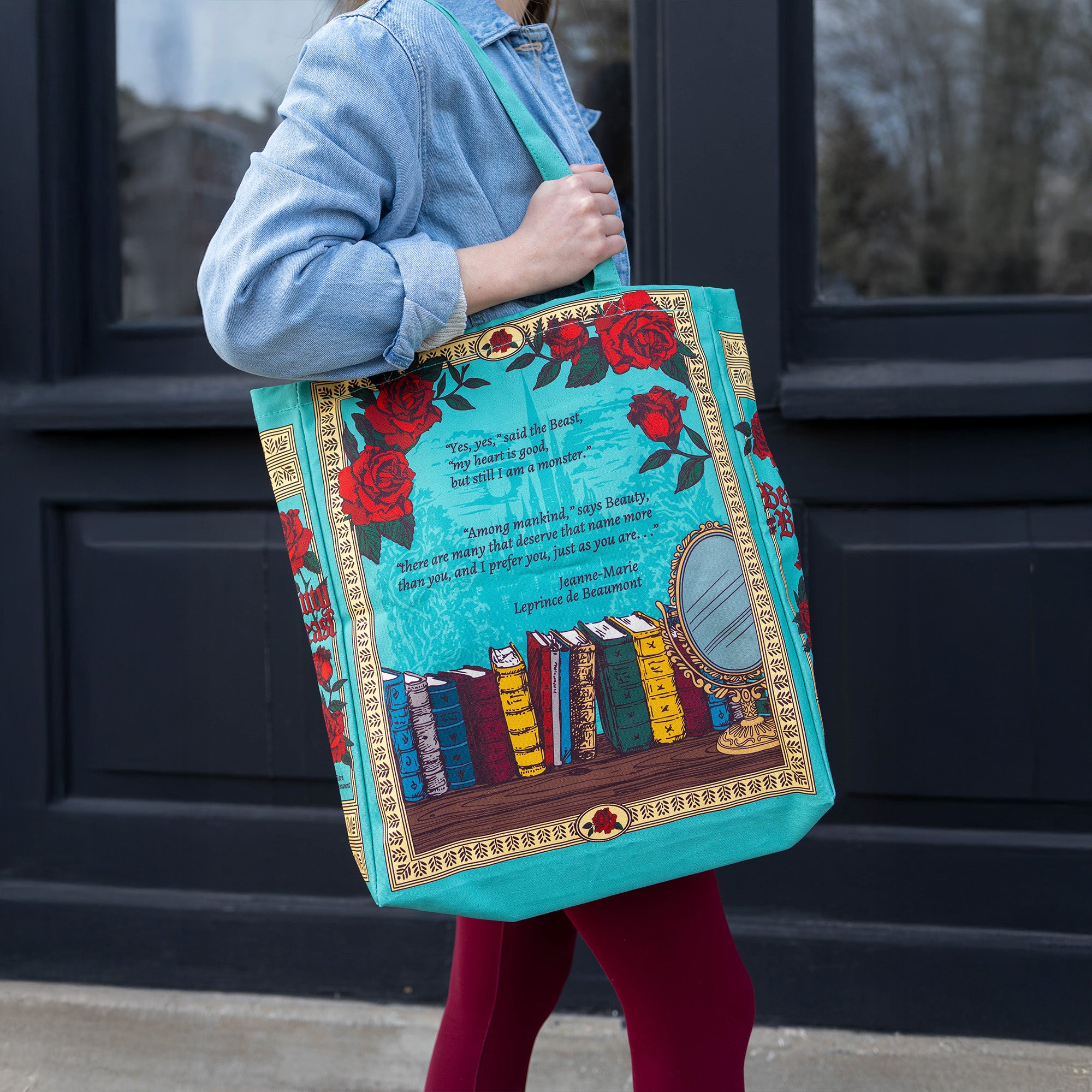 Person holding a colorful tote bag with book design and floral elements.