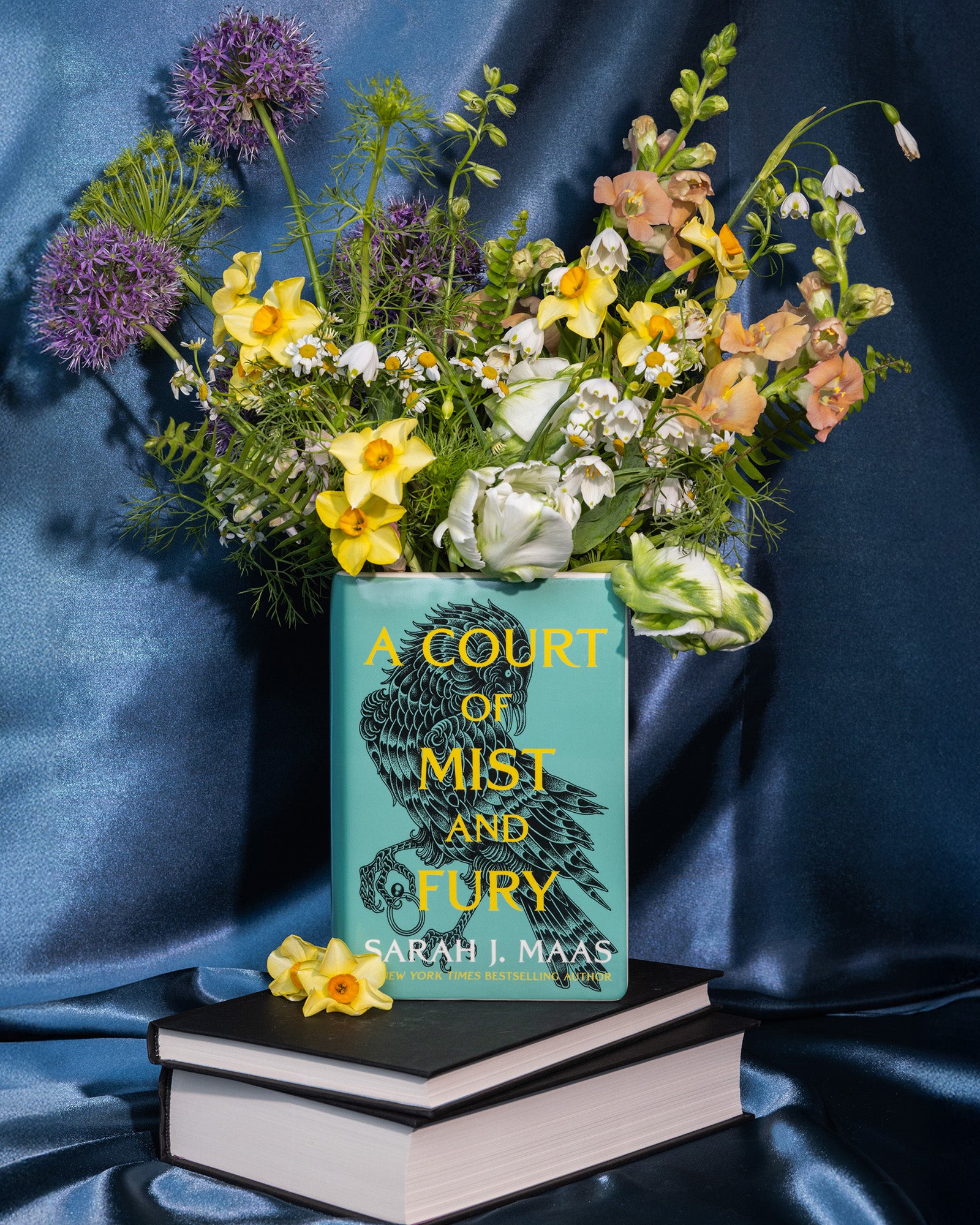 A Court of Mist and Fury' by Sarah J. Maas vase with a green cover and white spine and a bouquet inside