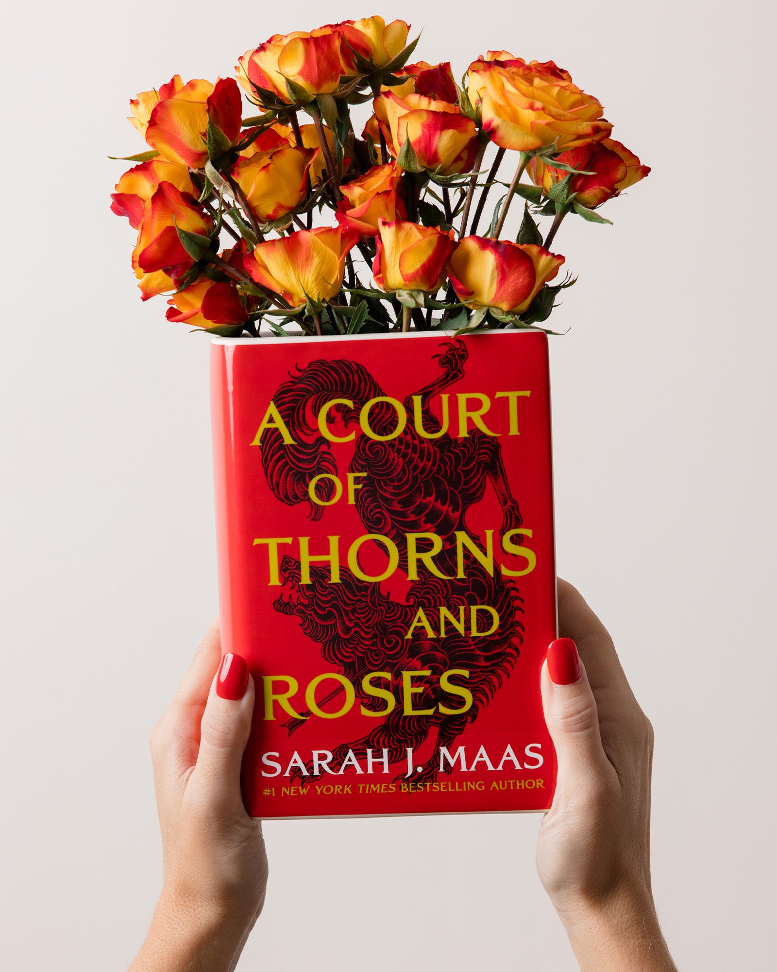 model holding book-shaped vase with 'A Court of Thorns and Roses' design