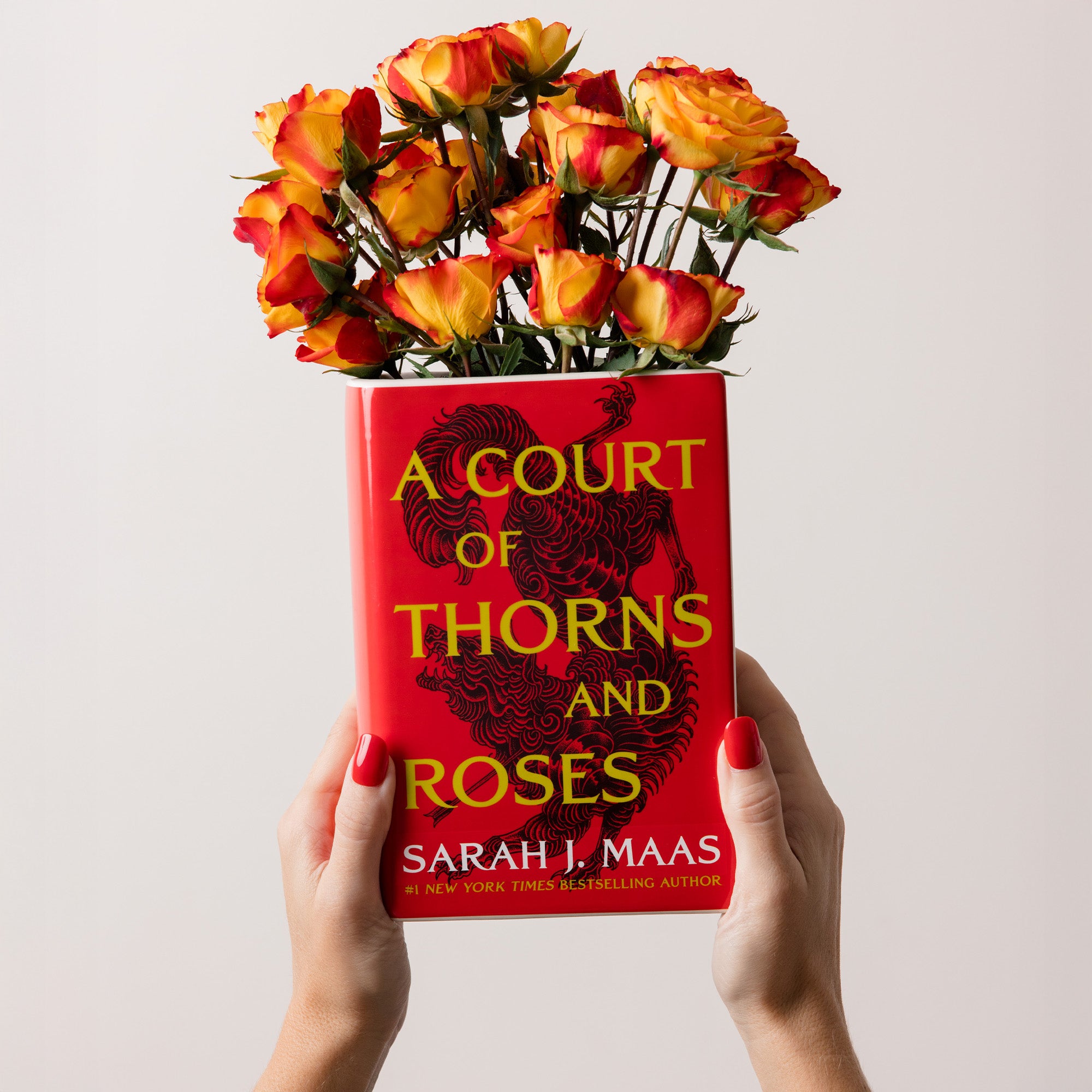 model holding book-shaped vase with 'A Court of Thorns and Roses' design