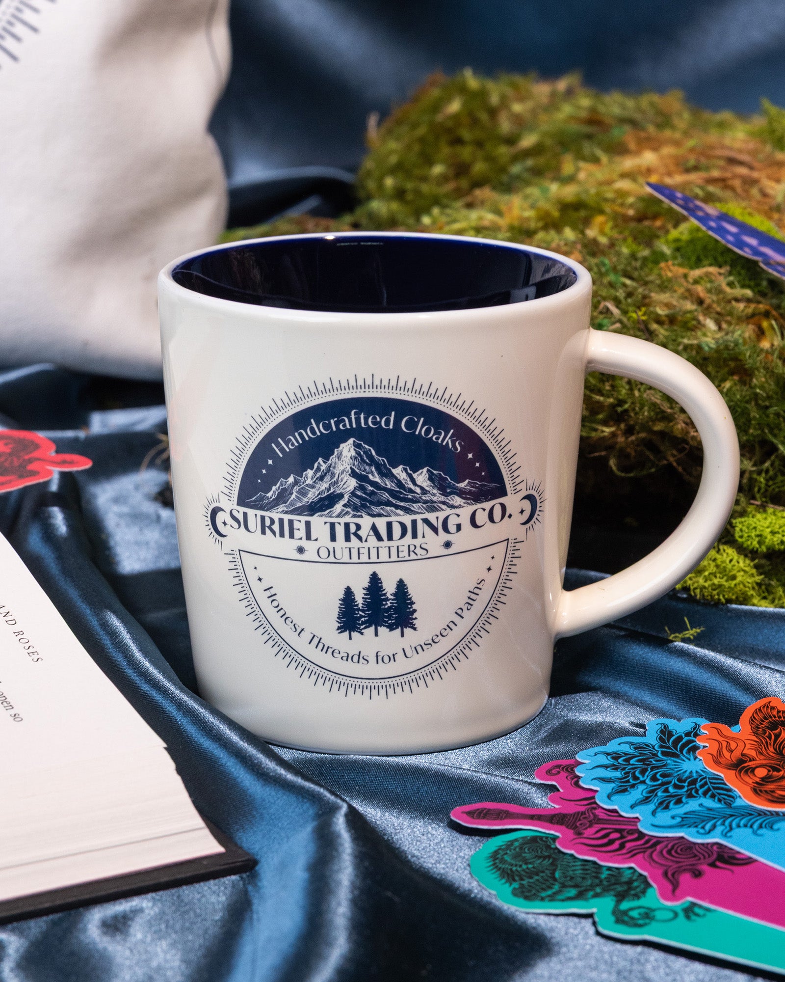 Beige mug with mountain and tree design and 'Suriel Trading Co.' text