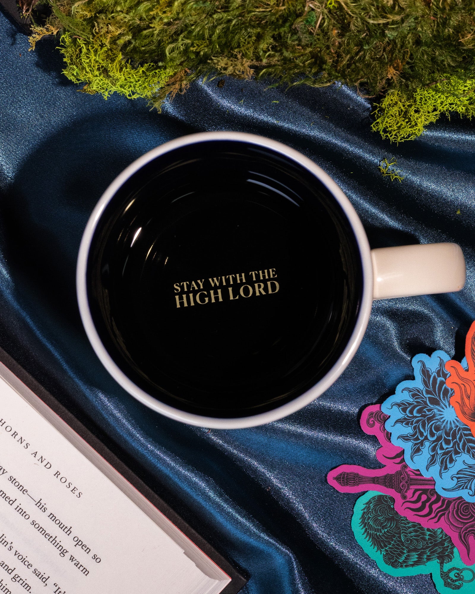interior 'STAY WITH THE HIGH LORD' of Beige mug with mountain and tree design and 'Suriel Trading Co.' text