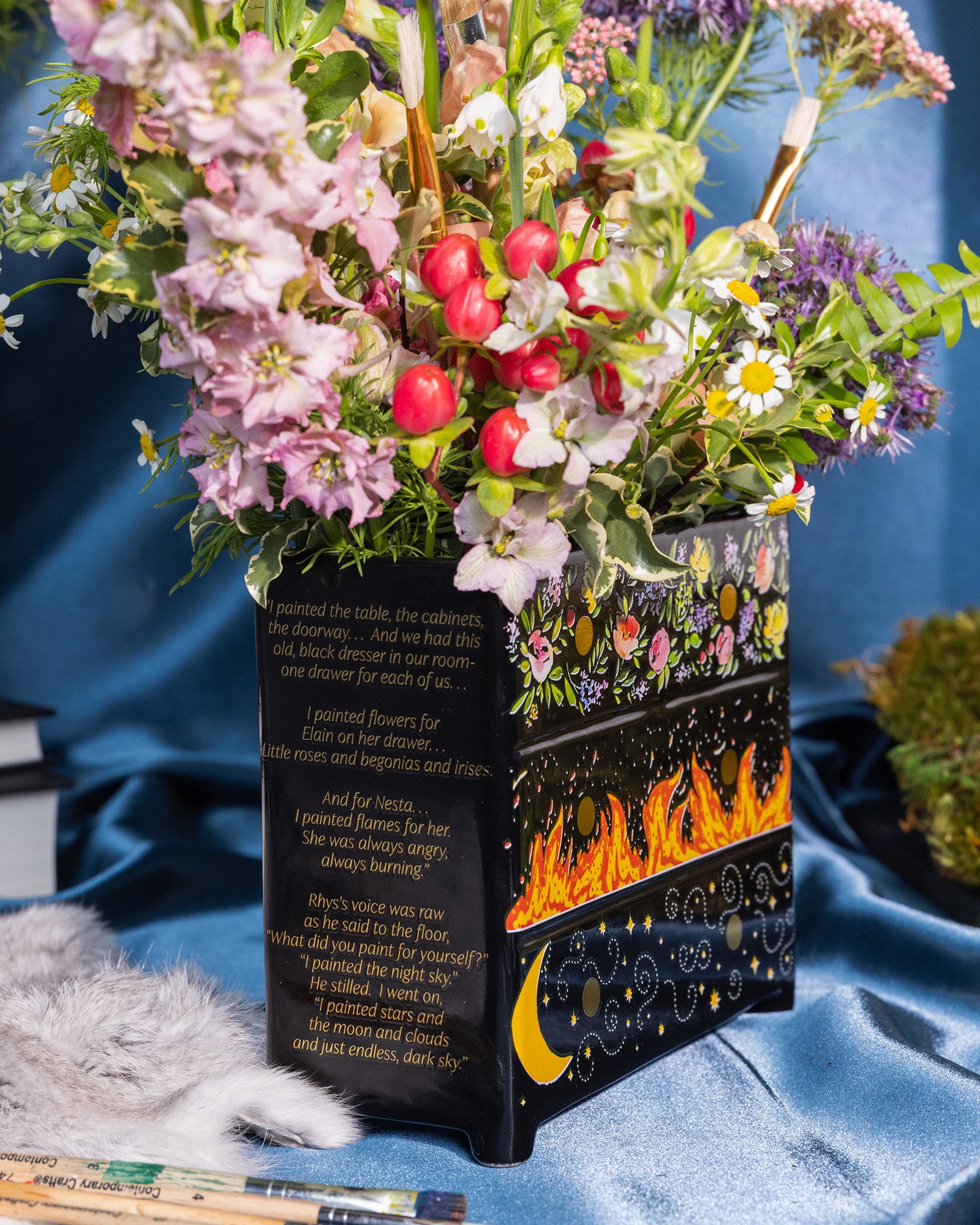 side view of Black planter with floral and fiery designs with a bouquet inside