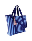 Sideview of dark blue and light blue striped tote bag with a tassel on a white background