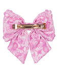 Pink floral bow with a gold clip on a white background