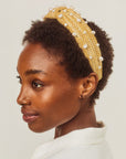 Woman wearing a raffia headband with pearls on a plain background
