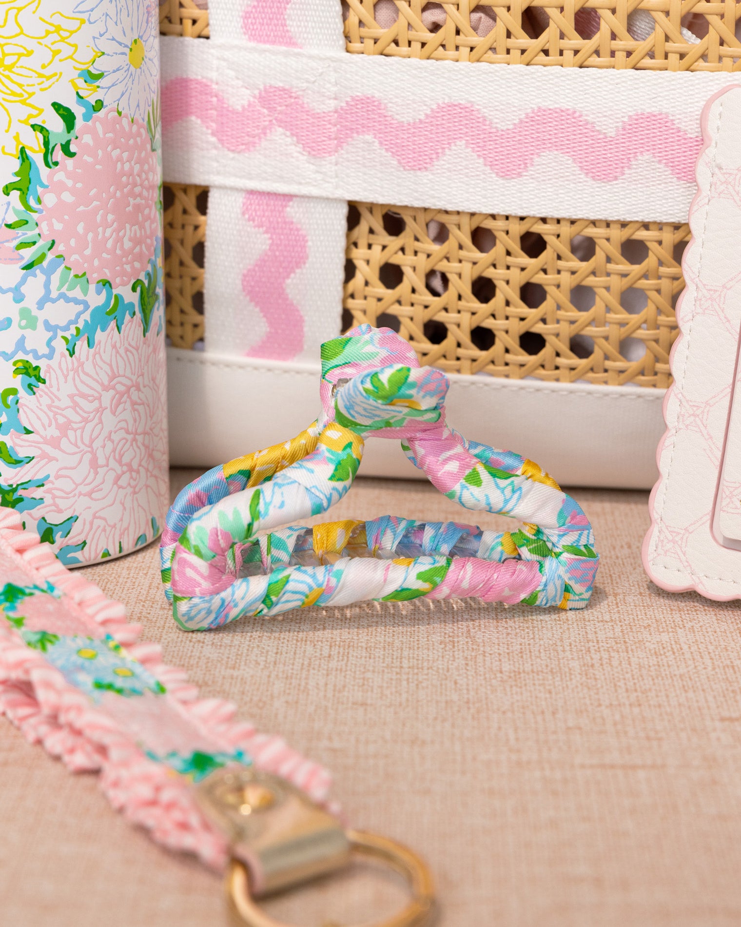 Floral-patterned strap with a gold clasp on a textured surface, with a wicker basket and floral fabric in the background.
