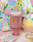 Colorful floral-patterned products including a tumbler, pouch, and bag on a matching floral background.