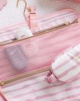 Pink travel set with mesh pouch and sleep mask on a matching background