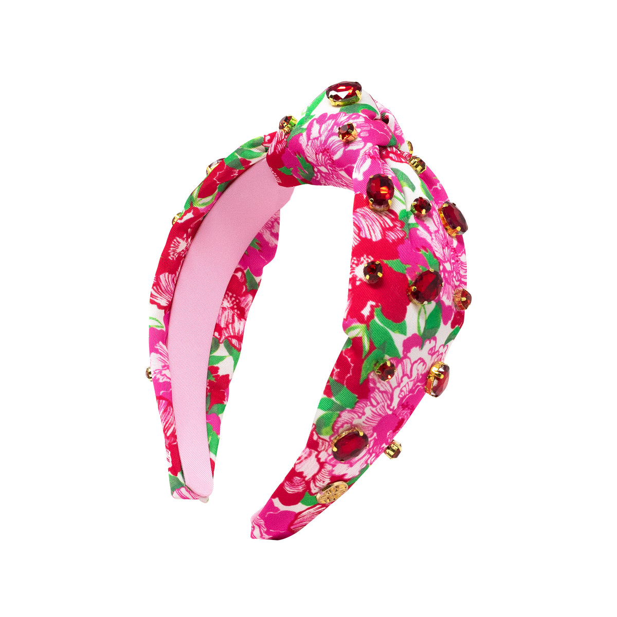 A twisted fabric headband featuring a vibrant pink floral print with green leaves, decorated with gold-tone beads and dark red jewel embellishments, shown against a plain white background.