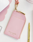 Pink cardholder with gold accents on a desk with office supplies