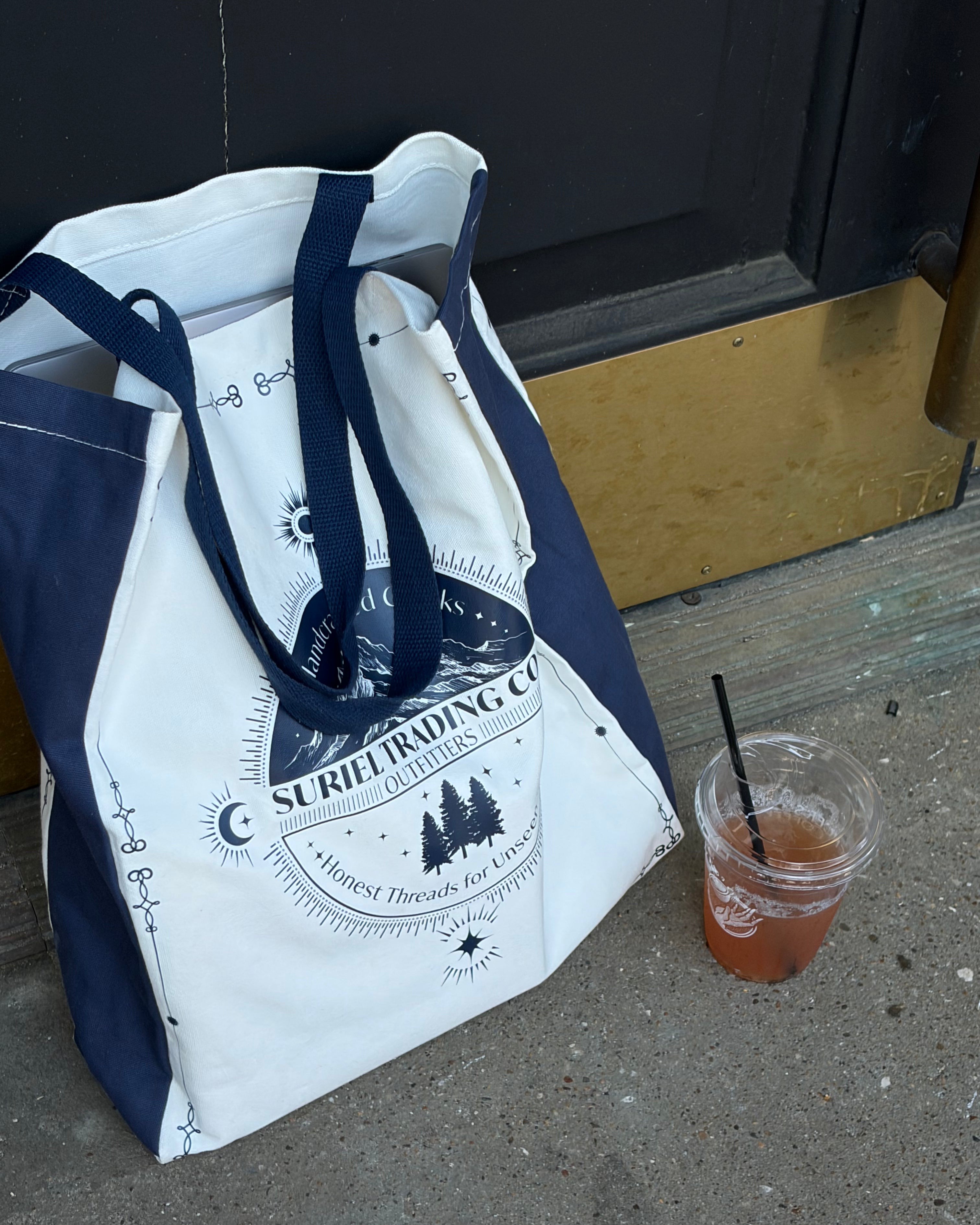 suriel trading co tote bag with a beverage next to it