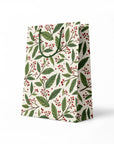 side view of gift bag with green leaf and red berry pattern on a white background