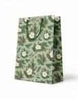 side view of green gift bag with white flowers and holly branches