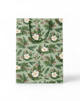 Green gift bag with white flowers and holly branches