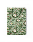 Flattened green gift bag with white flowers and holly branches