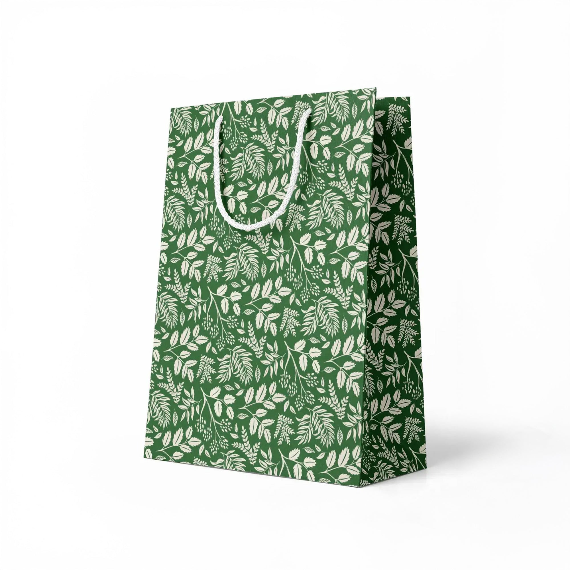 side view of green paper gift bag with white leaf pattern on a white background