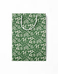 Flattened green paper gift bag with white leaf pattern on a white background