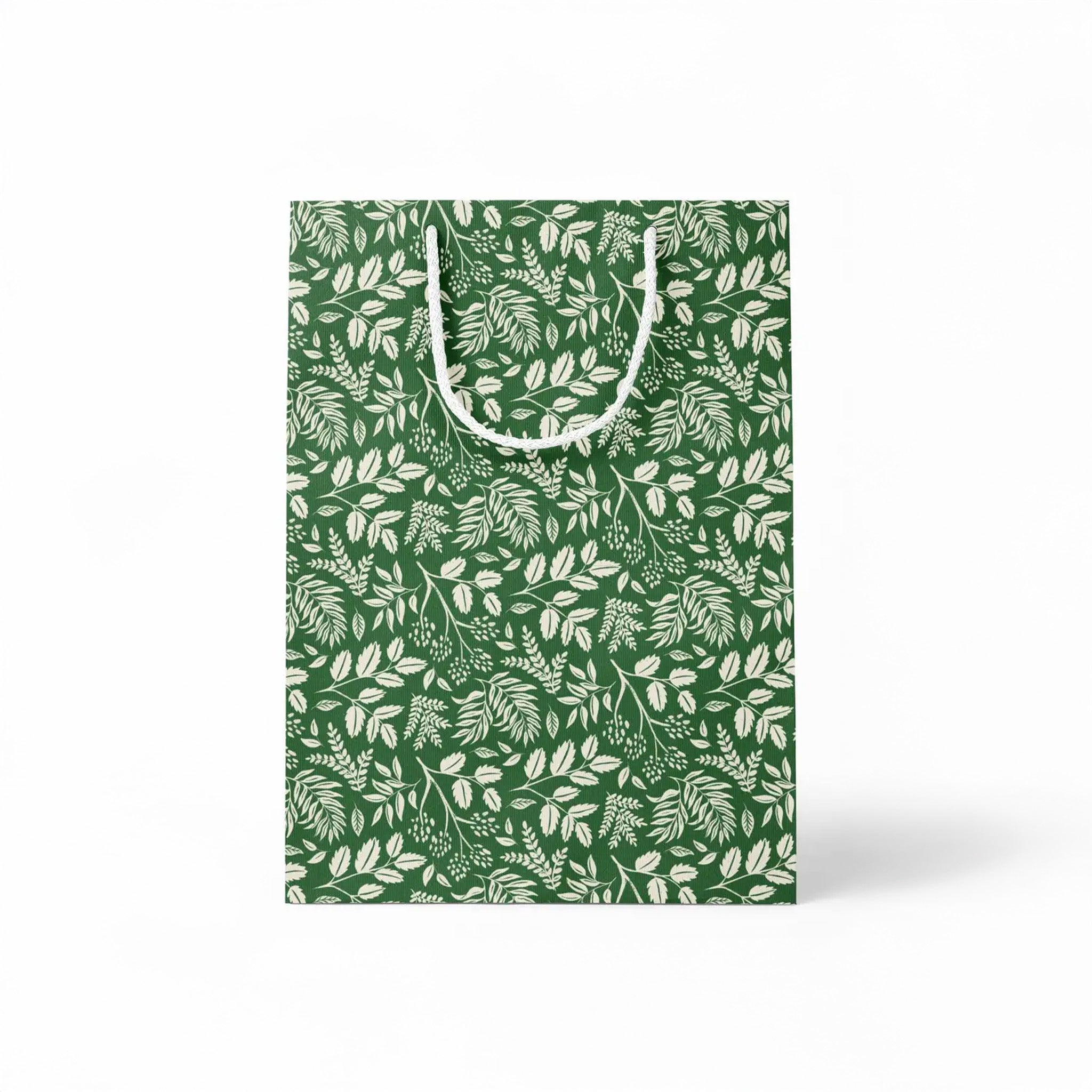 Green paper gift bag with white leaf pattern on a white background