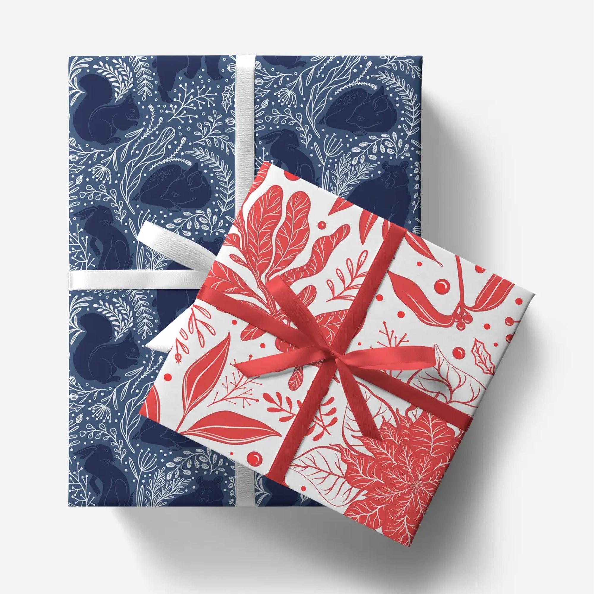 Two gift boxes with blue and white patterned box on top and red and white patterned box below, tied with ribbons.