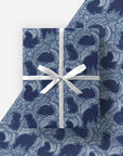 Blue patterned fabric with a white ribbon on a light gray background