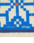 Close-up of a woven mat with blue and beige pattern, featuring the brand 'Kelsey Weigl'.