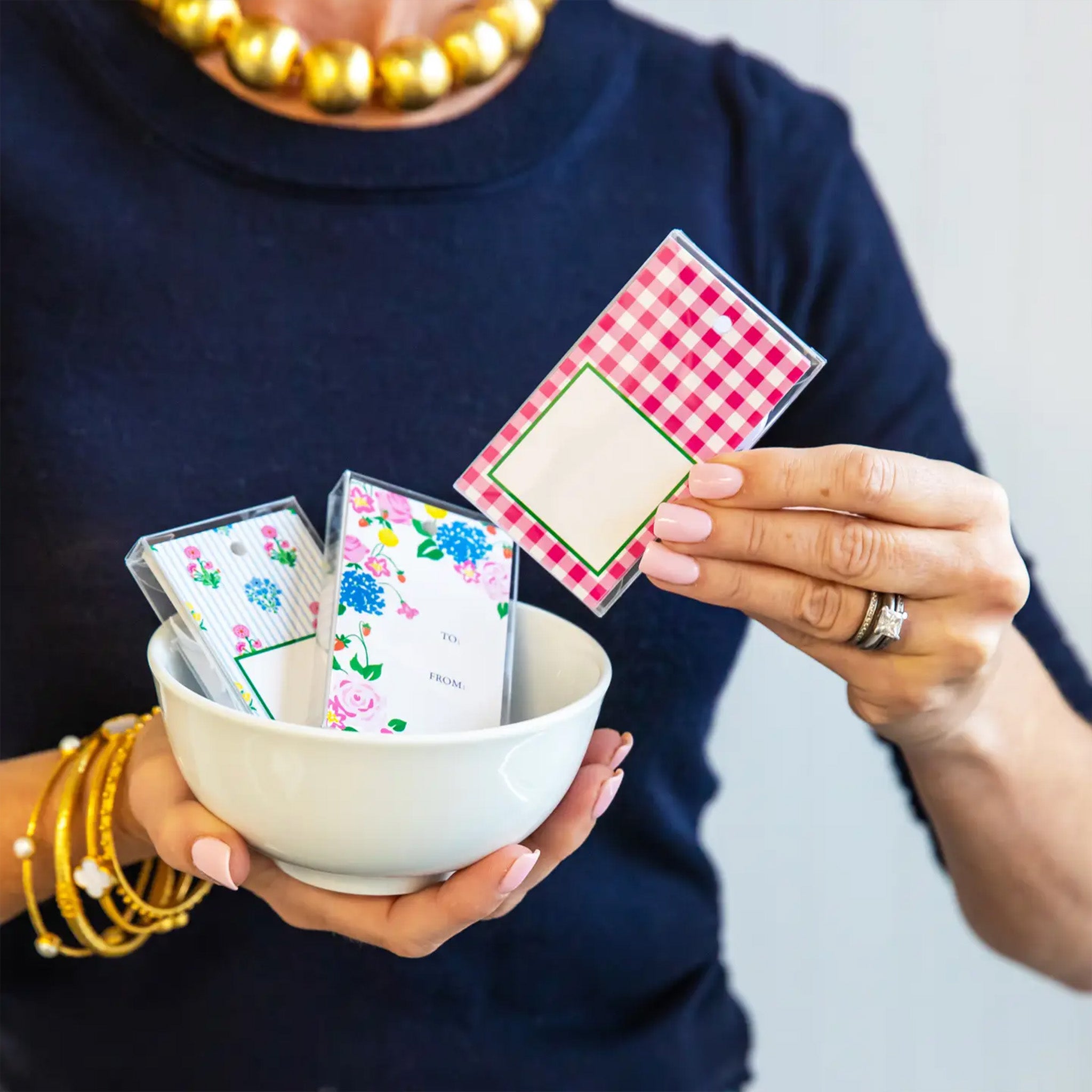 Person holding a bowl with playing cards and a deck of cards on a plain background