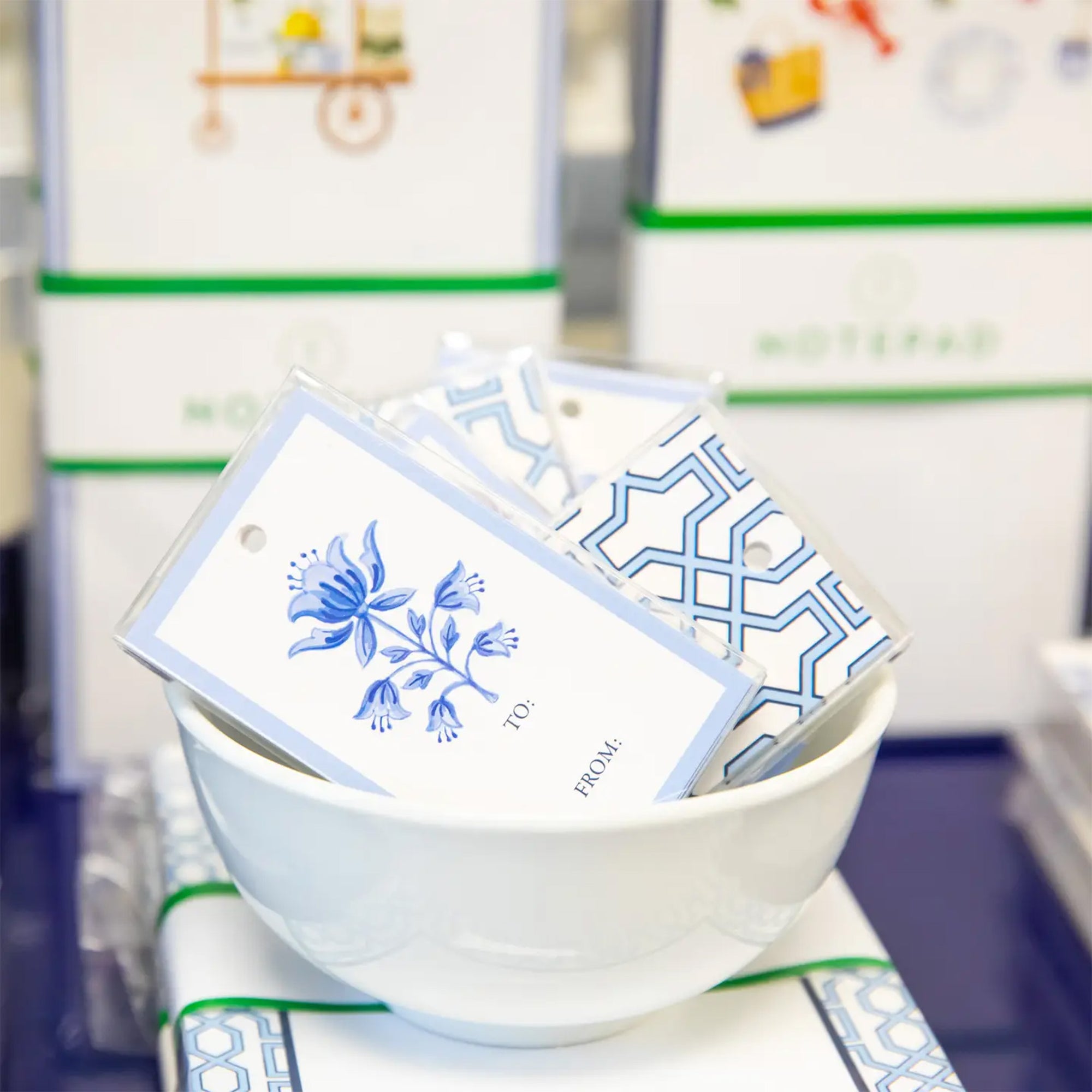 White bowl with blue floral and geometric designs on cards against a blurred store background