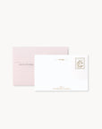 White card with gold text and pink envelope on a white background