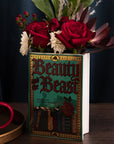 teal beauty and the beast book shaped vase with flowers inside