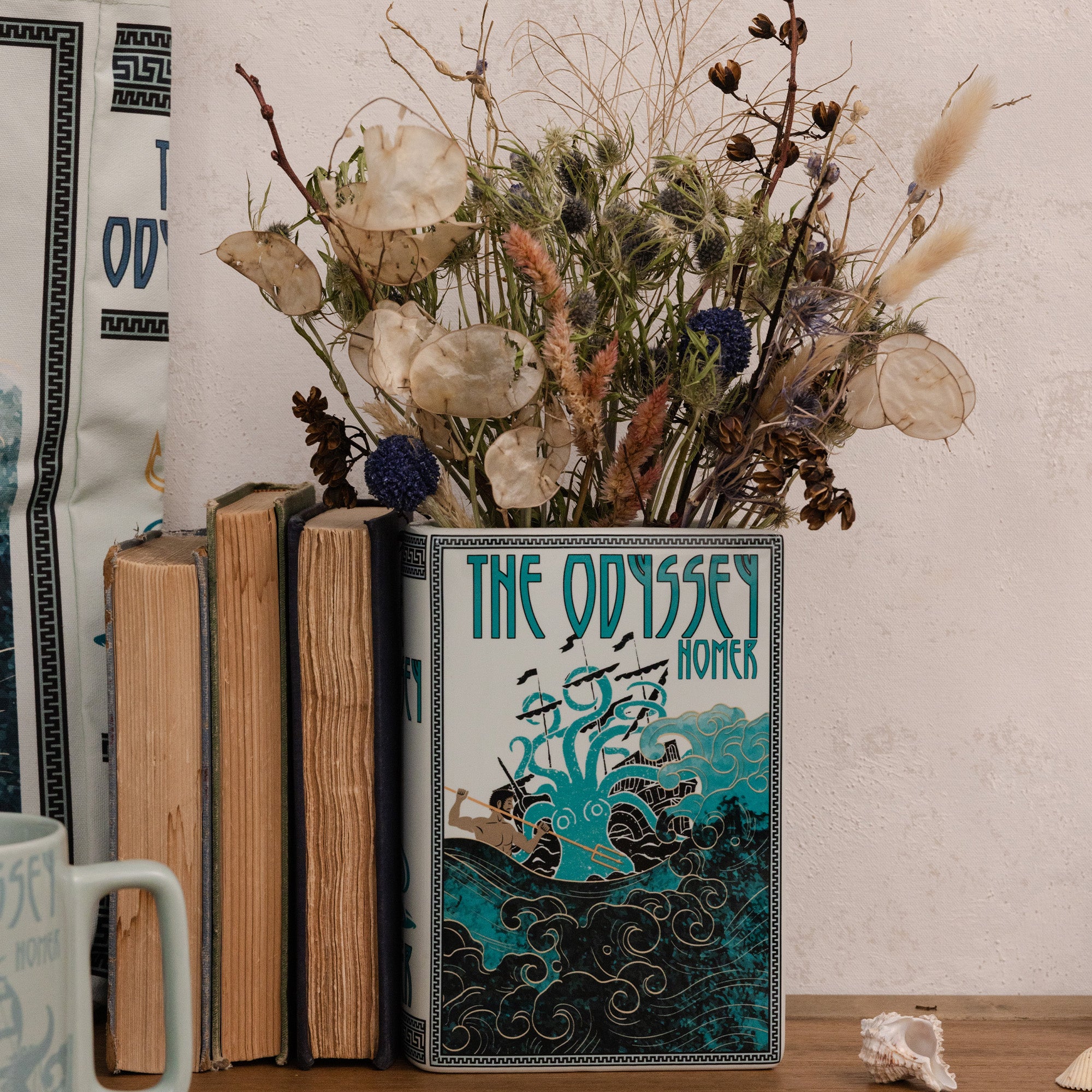 Book titled 'The Odyssey' by Homer with a decorative vase containing dried flowers on a wooden surface.