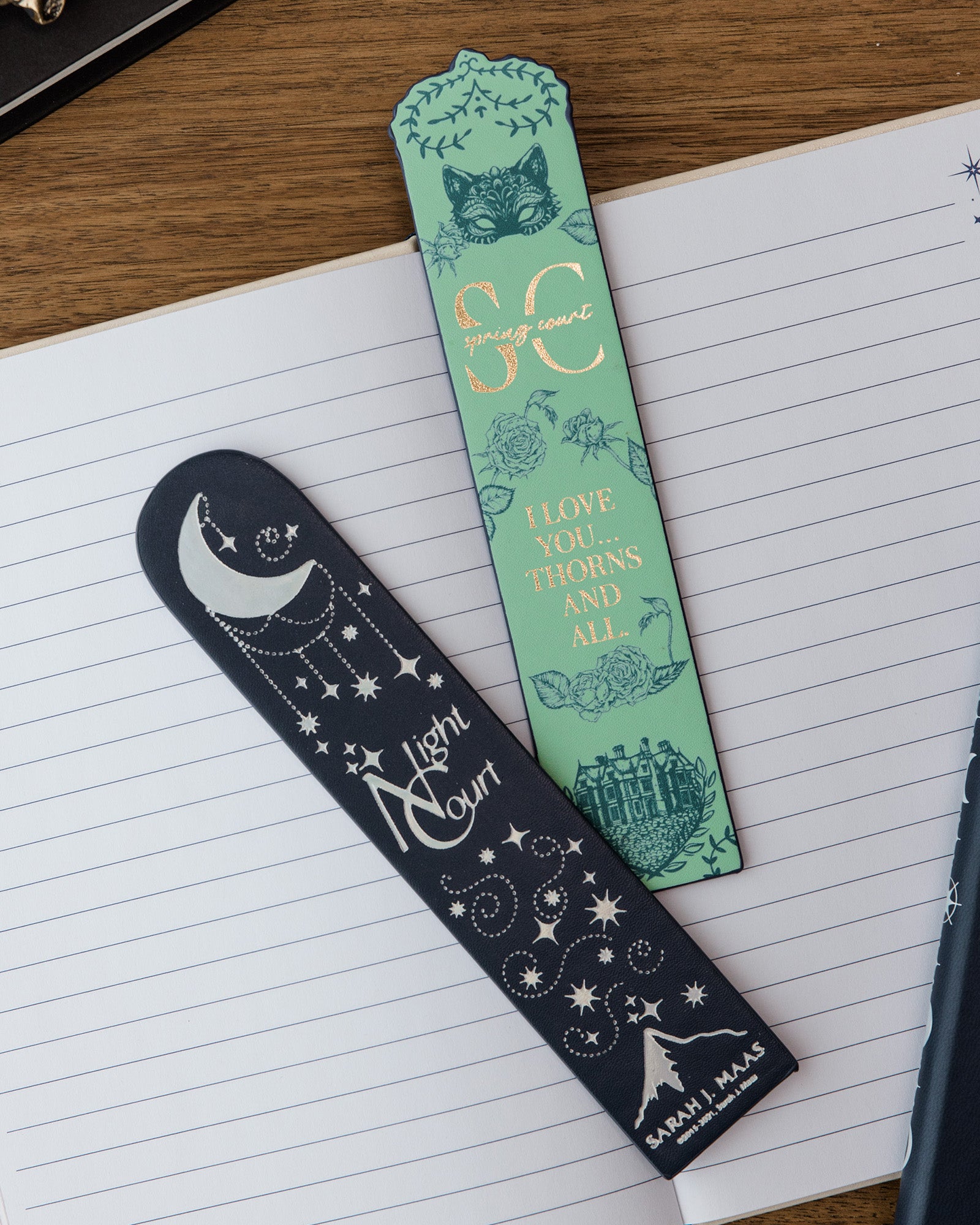 Two decorative bookmarks on a notebook with Spring and Night Court designs.