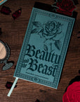 Teal notebook with rose design and 'Beauty and the Beast' text on a white background