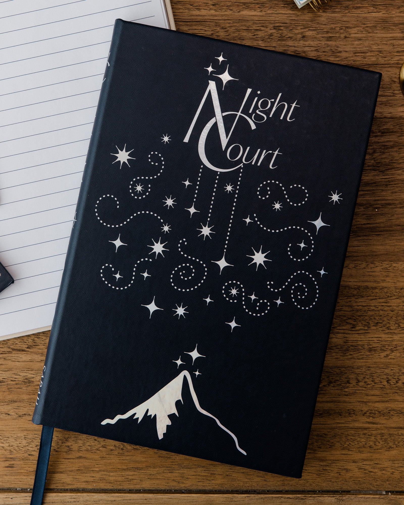 Black notebook with 'Light Court' design on a wooden surface