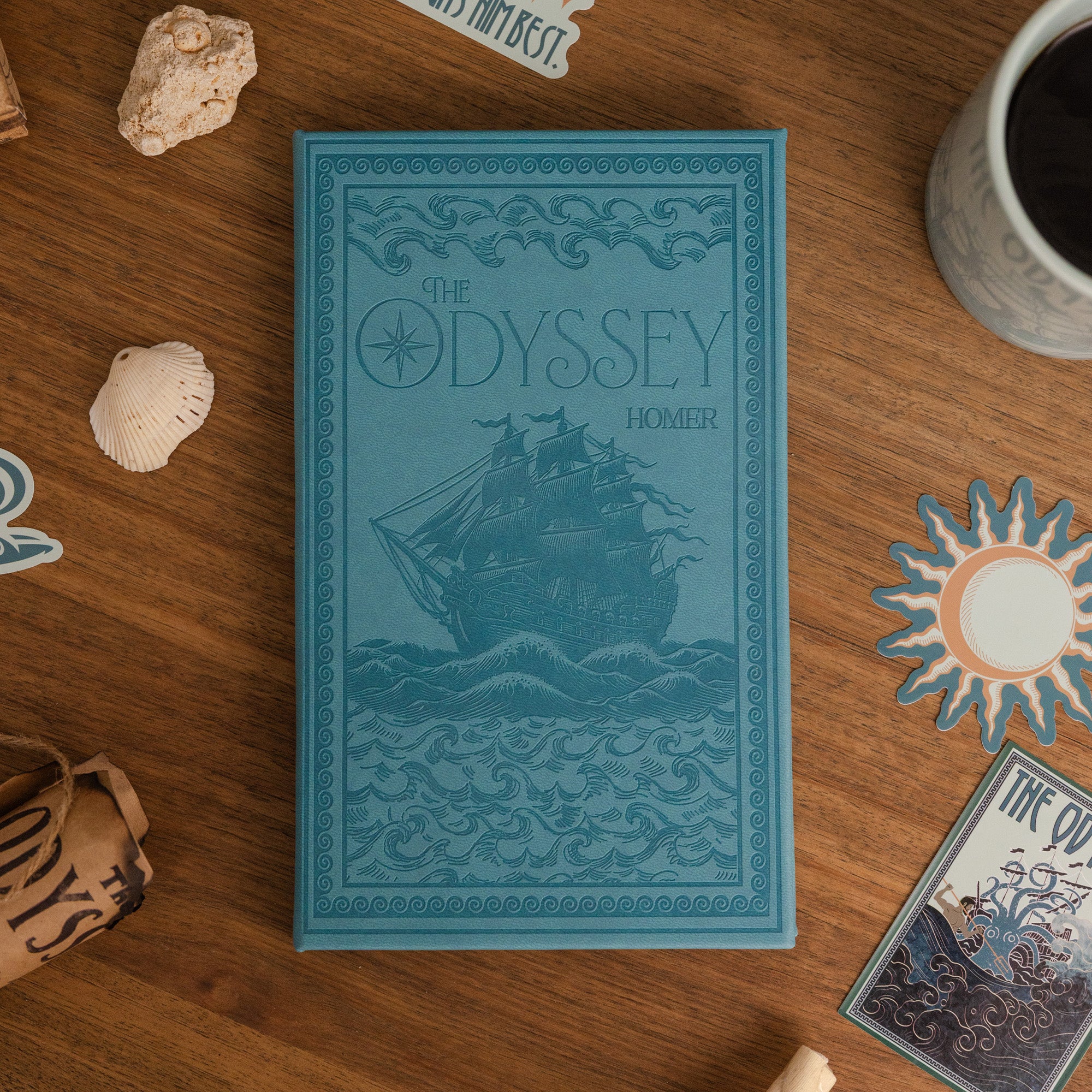 Blue book titled 'The Odyssey' by Homer on a wooden surface with decorative items.