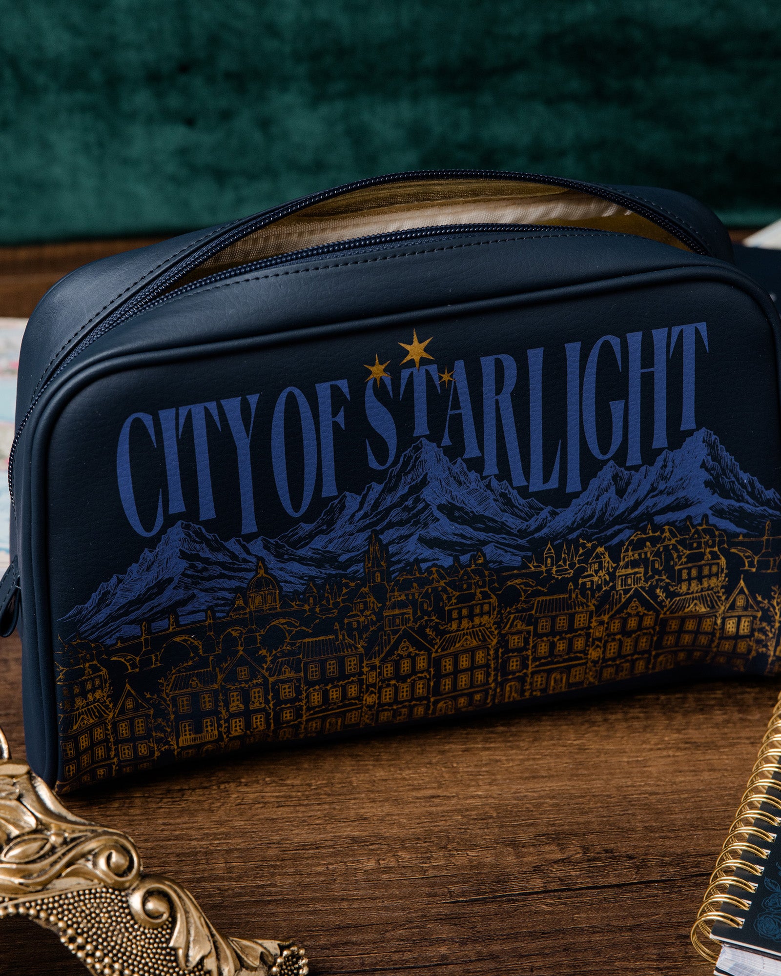 Navy blue pouch with 'City of Starlight' design on a wooden surface
