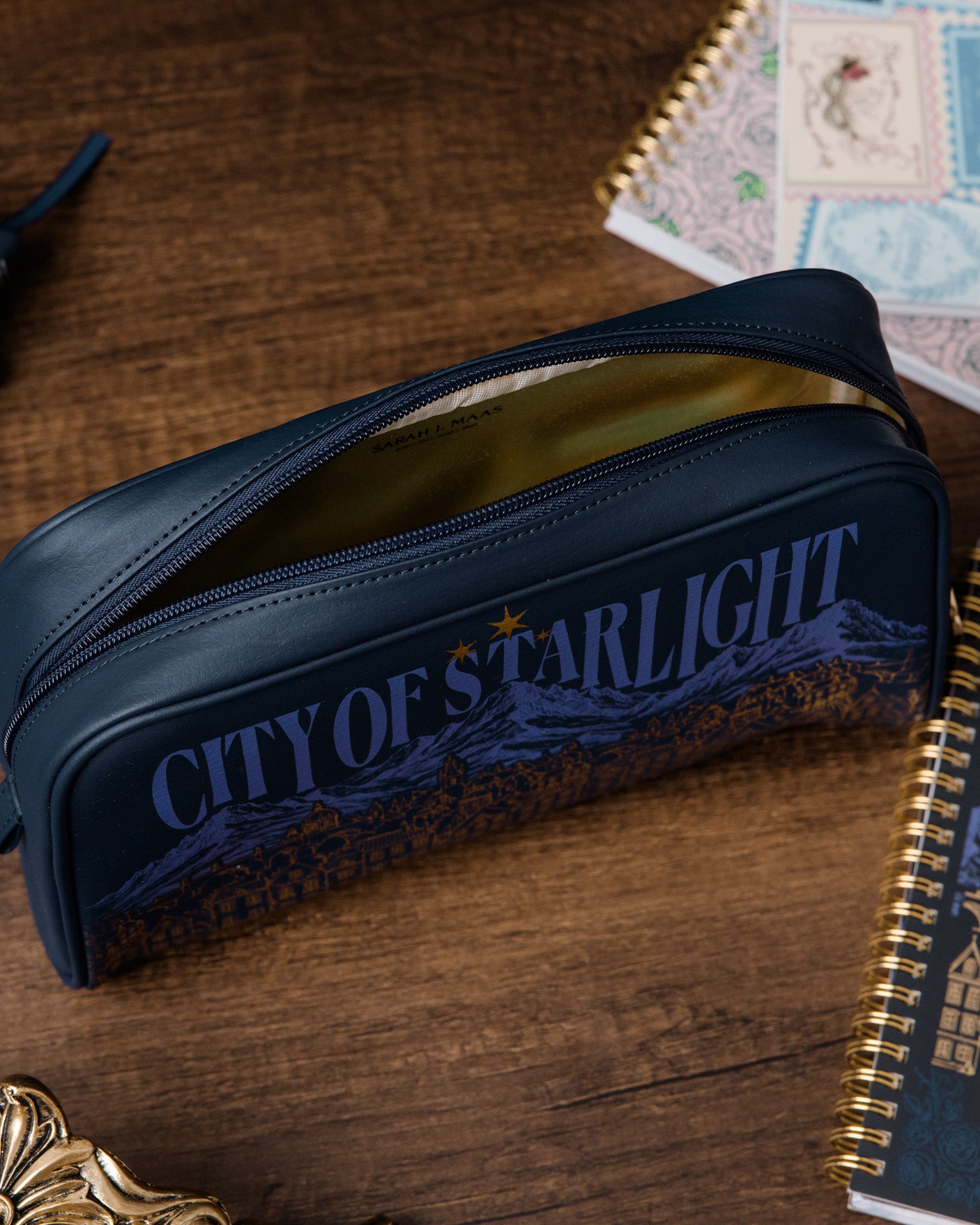 Blue case with 'City of Starlight' text on a wooden surface with books.